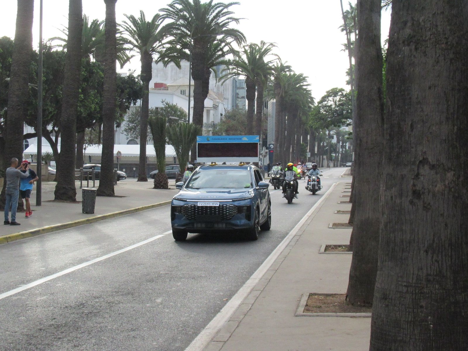Un véhicule participant au marathon, suivi des motos, photo gratuite