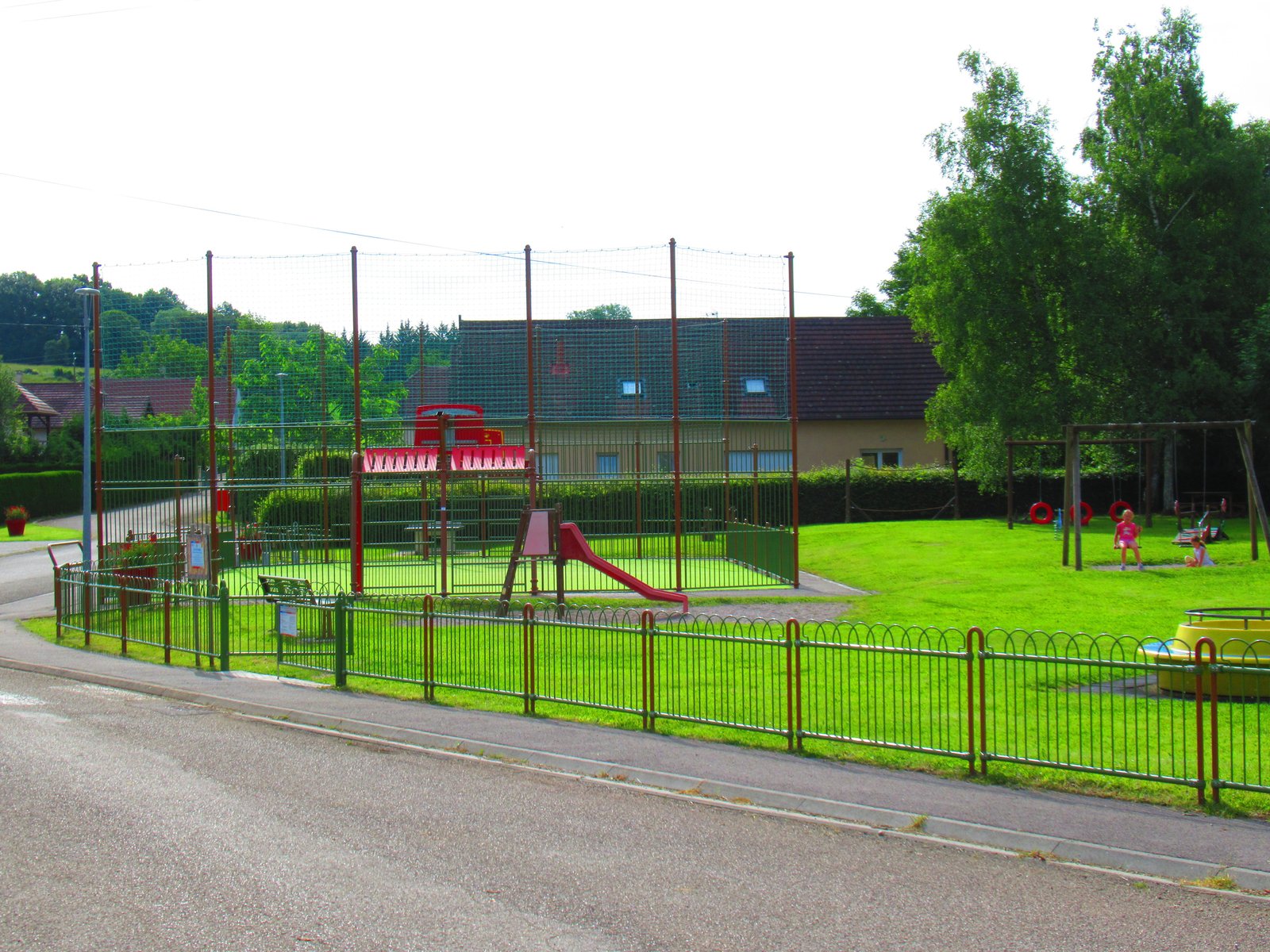 Une aire de jeux et un terrain multisport clôturé situés dans un espace public, parc, photo gratuite