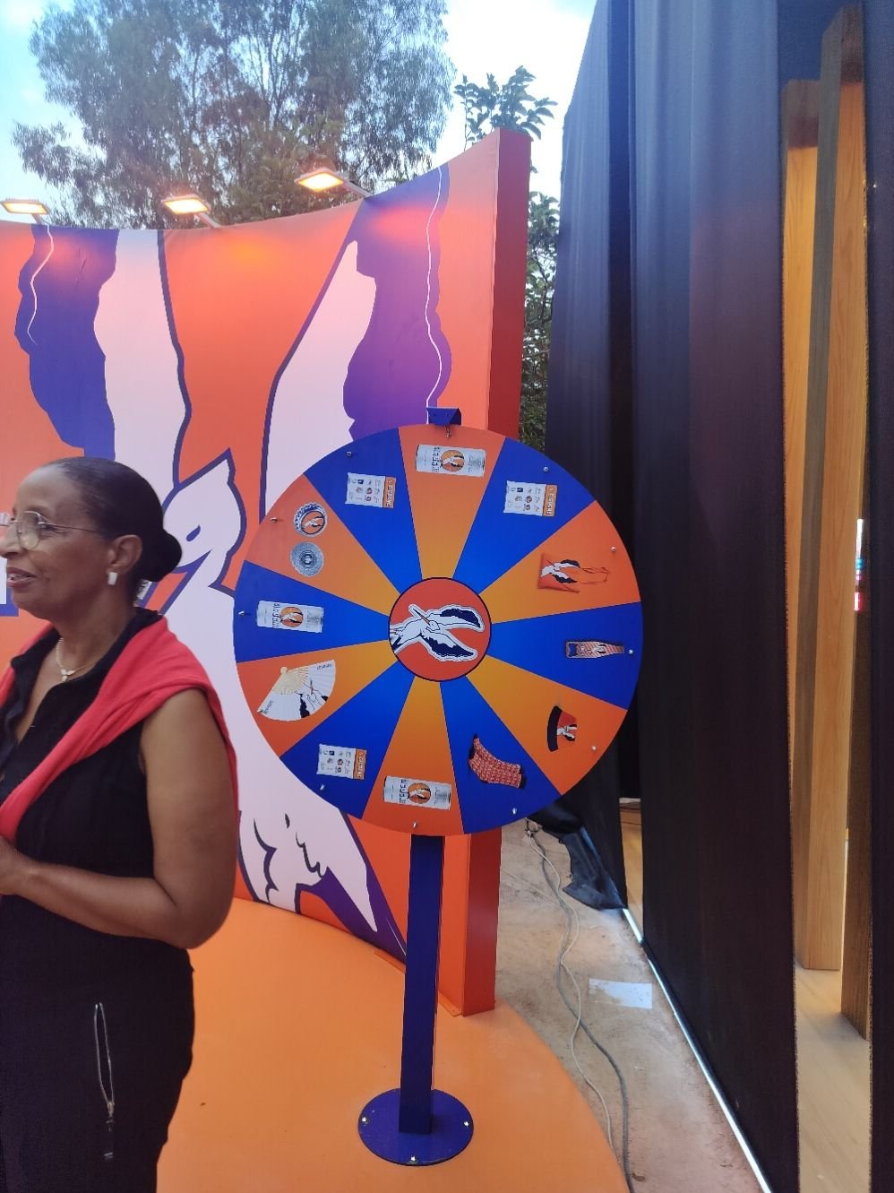 Une femme devant une roue de la fortune, un jeu de hasard où les participants font tourner une roue pour gagner des prix, photo gratuite