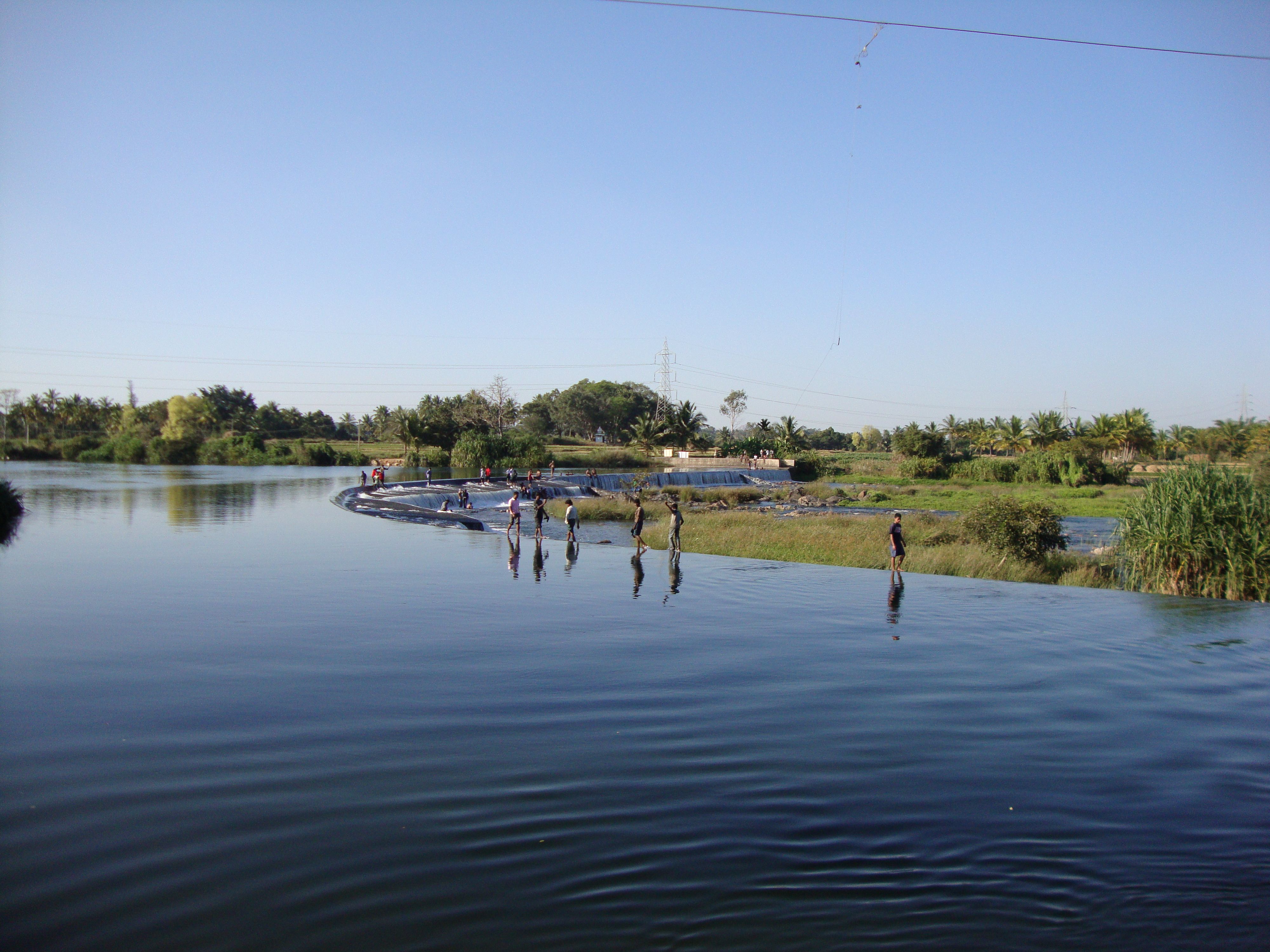 Un groupe de personnes se tenant dans une étendue d'eau, une rivière ou un lac, avec de la végétation et des arbres sur les rives, photo gratuite