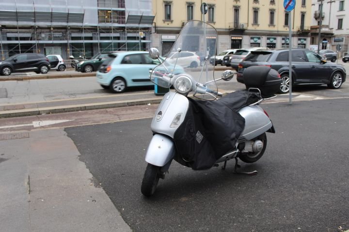 Moto Vespa GTS stationnée au bord d'un goudron dans la ville de Milan Lombardie en Italie photo gratuite