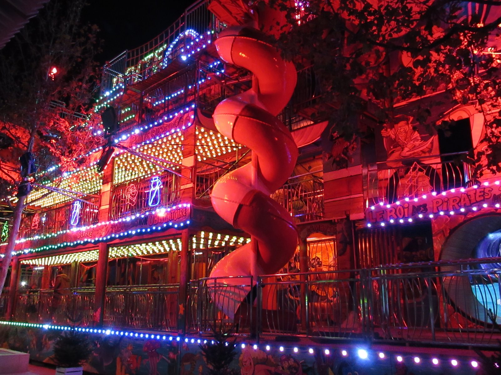 Edifice lumineux entourée de branche d'arbre, foire, fête foraine photo gratuite