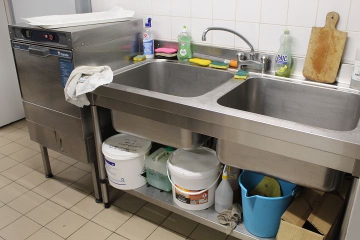 Un évier de cuisine professionnel en acier inoxydable avec deux bacs, un égouttoir, un robinet et des accessoires de nettoyage, photo gratuite