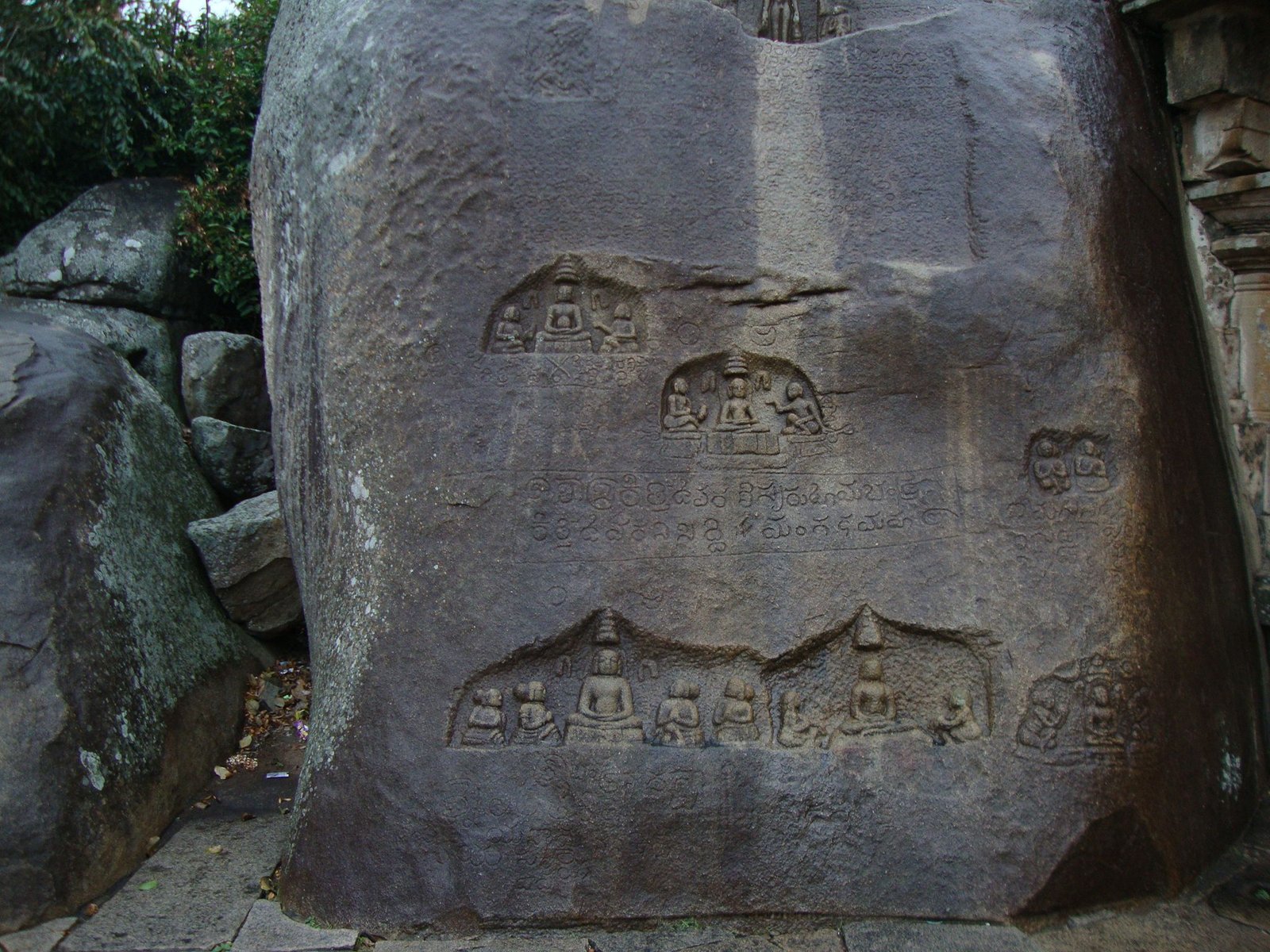Des reliefs sculptés sur un rocher, représentant des divinités bouddhistes et des inscriptions, photo gratuite