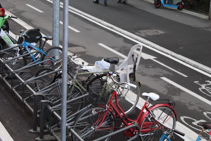 Rental bikes parked in a bike rack next to a bike path, free photo