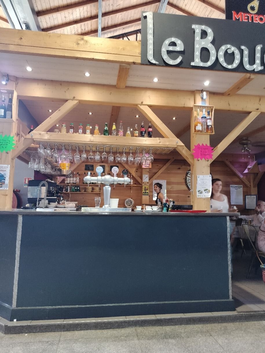 Un long comptoir avec un distributeur de bière et des rangées de verres suspendus au-dessus, photo gratuite