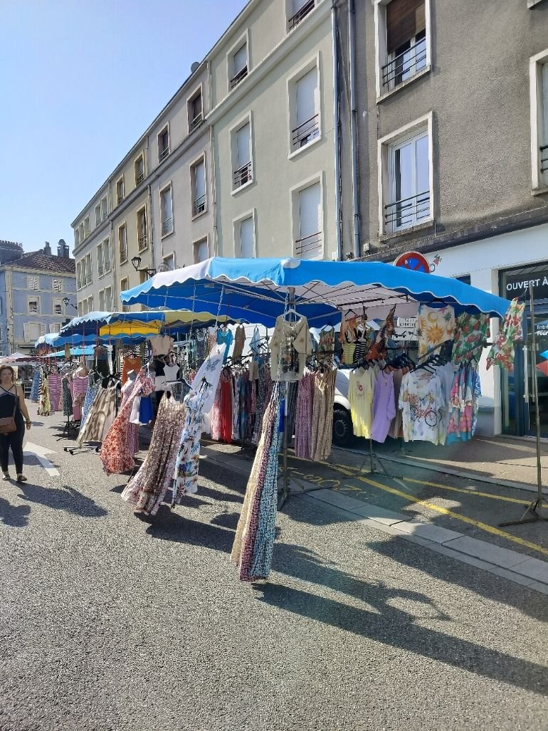 Un marché en plein air, plusieurs stands de vêtements installés le long d'une rue, sous des parasols, photo gratuite