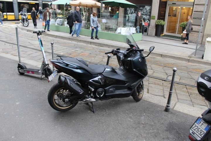 Une moto Yamaha TMAX 560 garée au bord du goudron et une trottinette électrique, photo gratuite