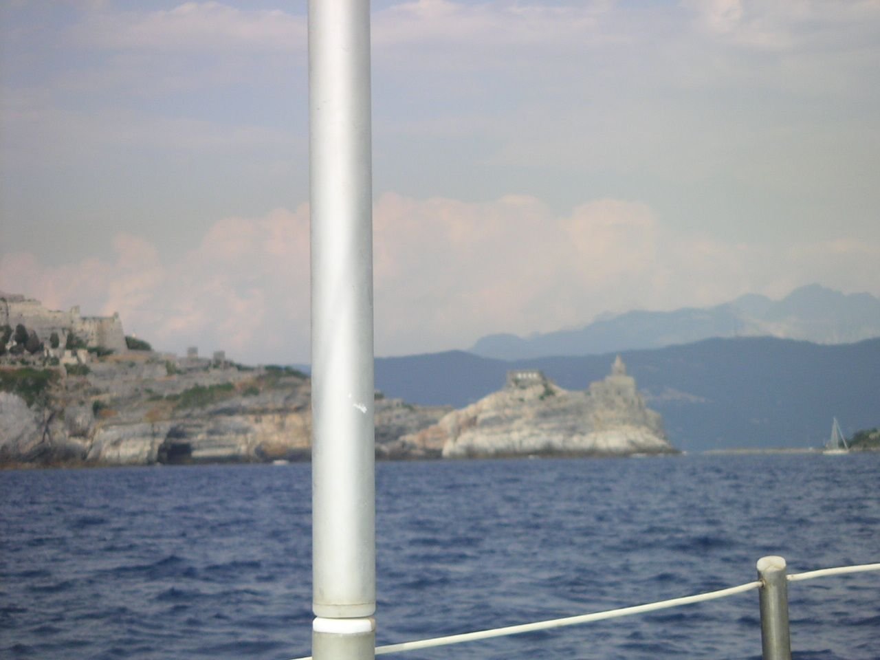 Une étendue d'eau, suggérant la mer, avec un mât de bateau et une balustrade visible, indiquant une perspective depuis un navire ou un quai, un paysage côtier méditerranéen en Italie, photo gratuite