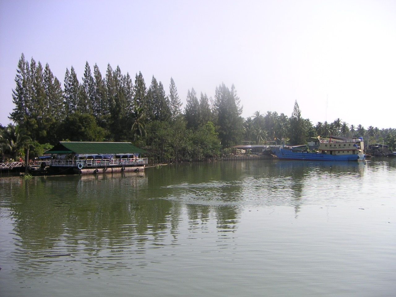 Une étendue d'eau calme, reflétant le ciel et la végétation environnante, plusieurs bateaux sont visibles sur l'eau, photo gratuite