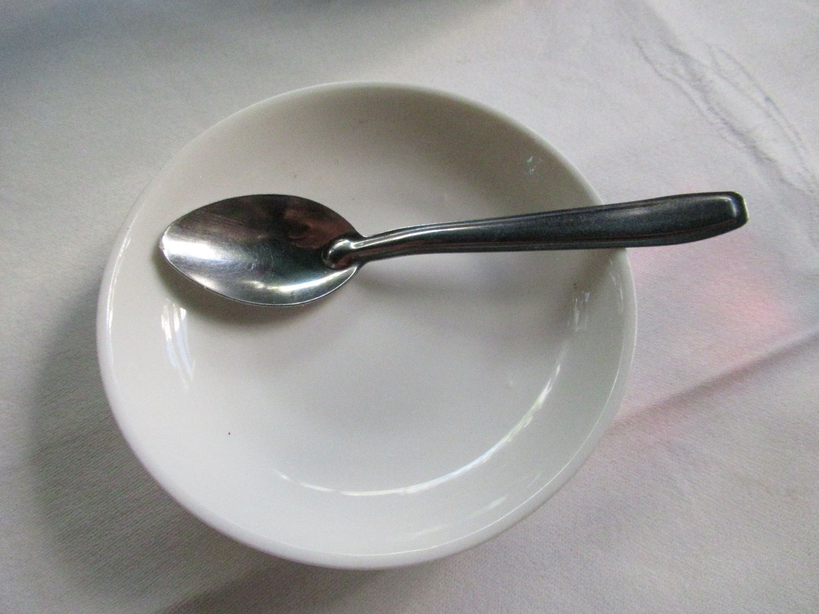 Cuillère à soupe en acier sur une assiette en porcelaine blanche