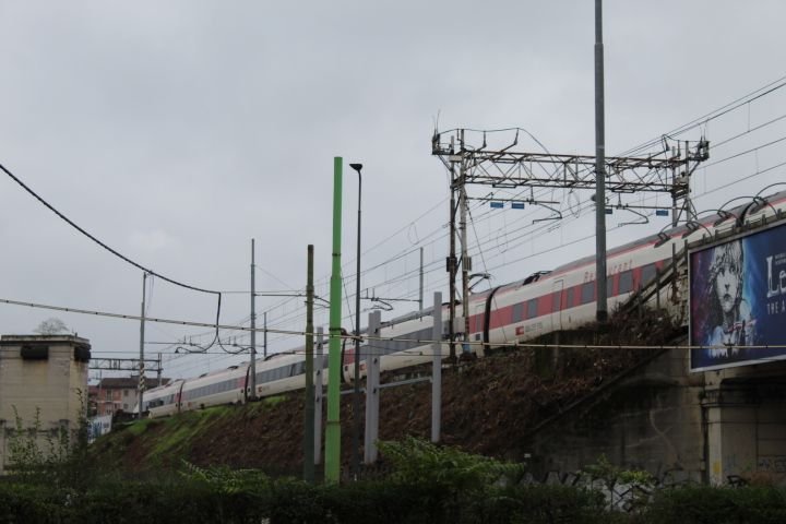 Un train sur une voie ferrée surélevée, des poteaux supportant des câbles électriques et des éléments de signalisation ferroviaire, photo gratuite