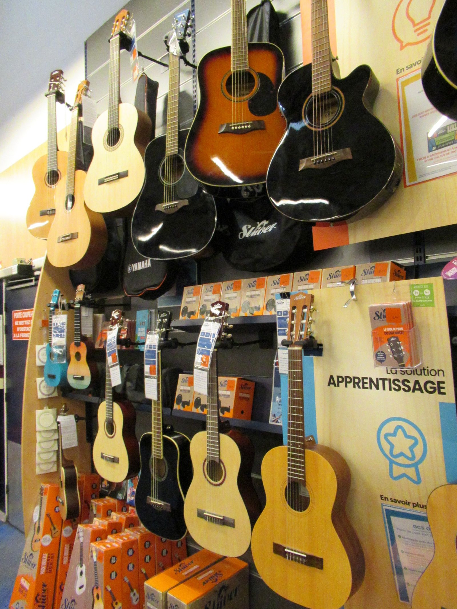 Gamme de Guitares classiques et acoustiques suspendues dans un magasin