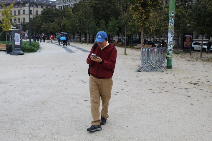 Une personne marchant dans un espace public, un parc, tout en consultant son téléphone portable, photo gratuite