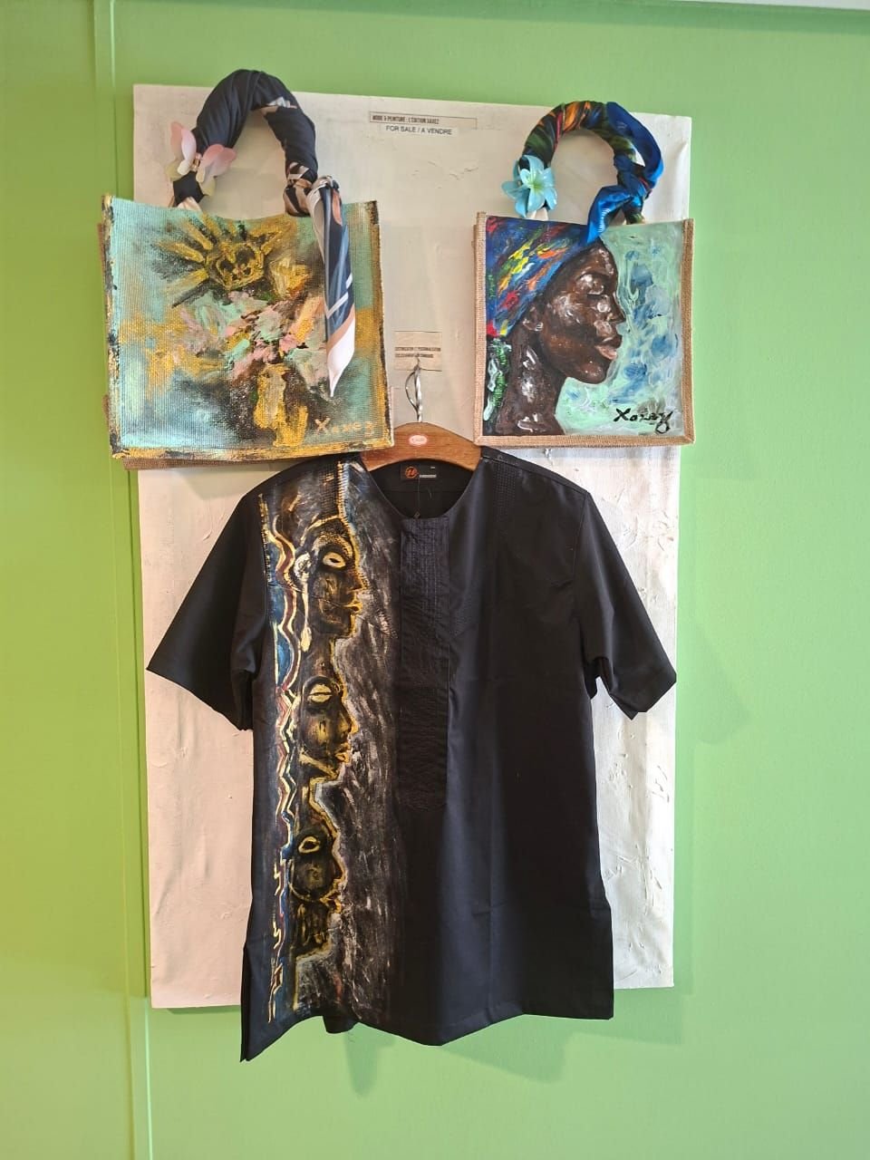 Un ensemble de sacs à main artisanaux peints et d'une chemise noire ornée de motifs artistiques de style africain, photo gratuite