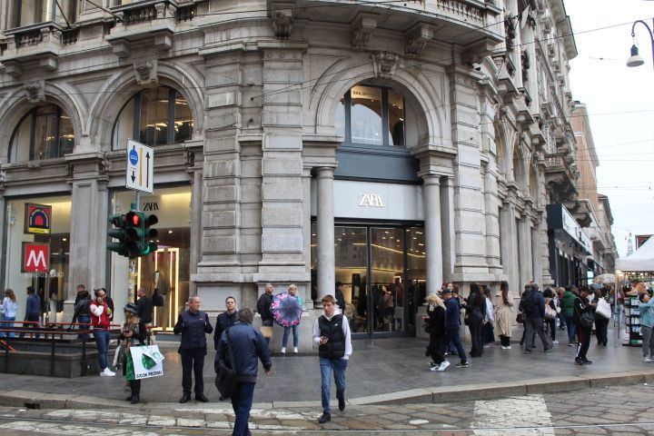 A busy street with a large Zara store on the corner of a building, free photo