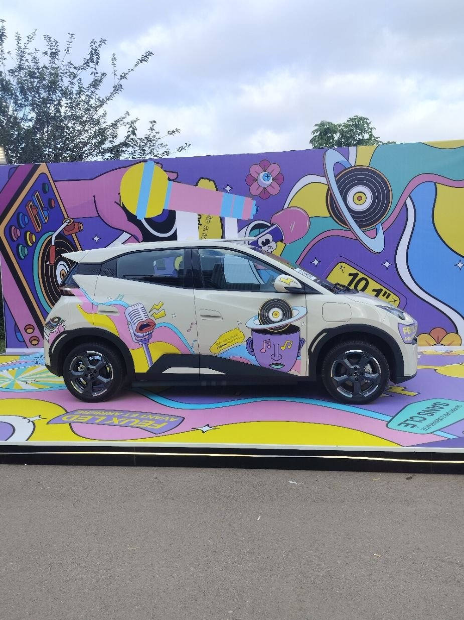 A BYD Seagull, a small electric city car, in front of a wall covered in graffiti, free photo