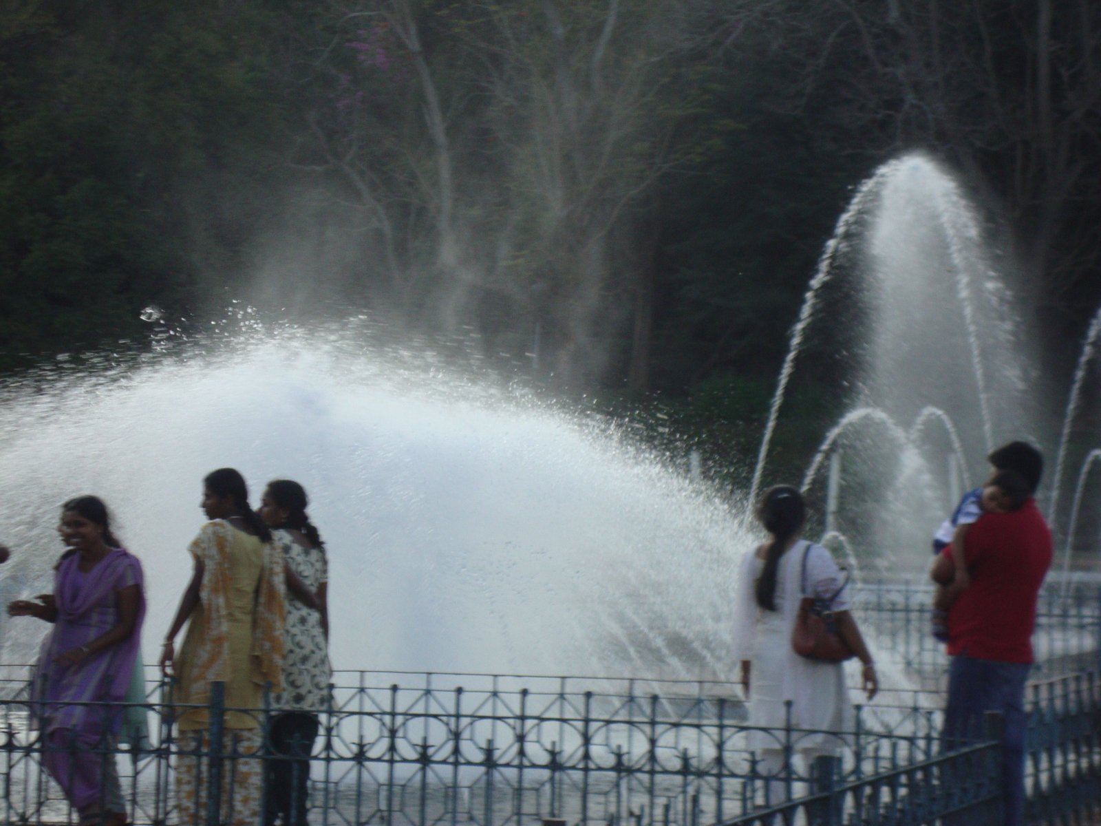Une fontaine à eau, avec des jets d'eau s'élevant dans les airs, observée par une famille, photo gratuite