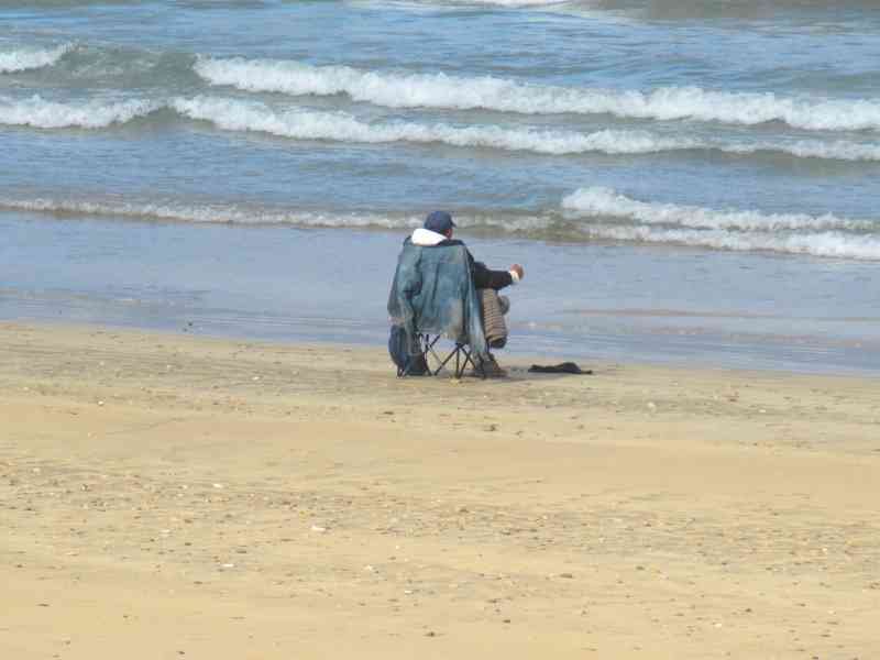 Une personne assit sur une chaine au bord de la mer photo gratuite