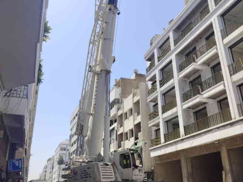 Une grue mobile tout-terrain devant un immeuble en construction, photo gratuite