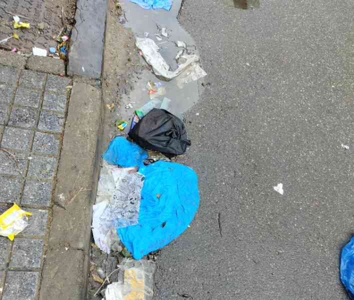 Des déchets et des ordures jonchant le sol près d'un trottoir et d'une flaque d'eau, photo gratuite