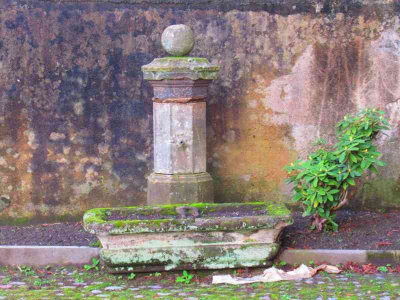 Old stone fountain against a worn wall free photo