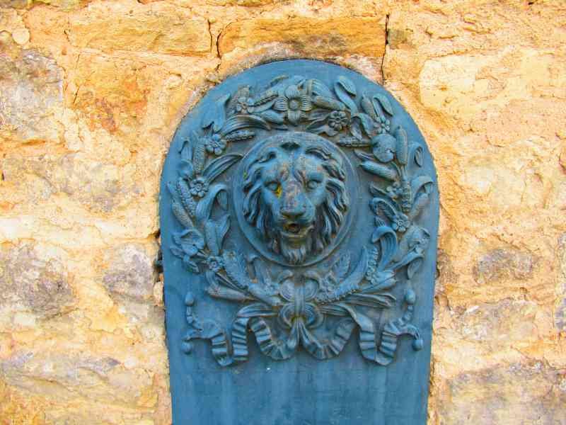 Une tête de lion en relief entourée de motifs floraux et végétaux fixée sur un mur en pierre, une fontaine, photo gratuite