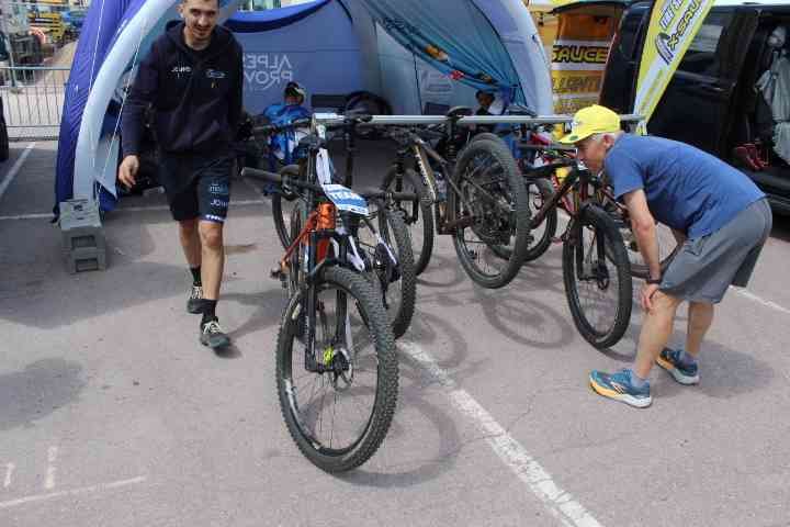 Vélos sur un support, et deux personnes sont visibles, l'une en train de marcher vers le support et l'autre en train de vérifier un vélo, photo gratuite