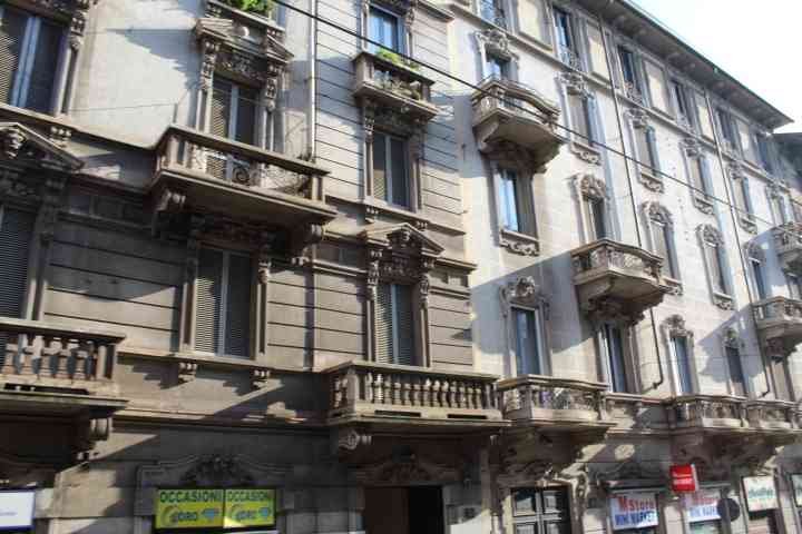 Un immeuble avec des balcons ornés et des volets, typique de l'architecture urbaine milanaise, photo gratuite