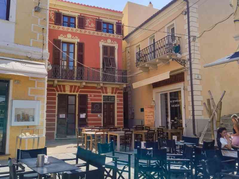 Des bâtiments qui environnent une terrasse avec des tables et des chaises, photo gratuite