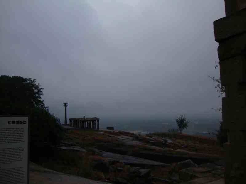 Une vue sur le paysage environnant, le temple de Chandragiri à Shravanabelagola, avec des structures architecturales et une végétation clairsemée sous un ciel nuageux, photo gratuite