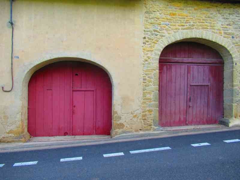 Deux portes en bois rouge situées dans un mur de pierre au bord du goudron, photo gratuite