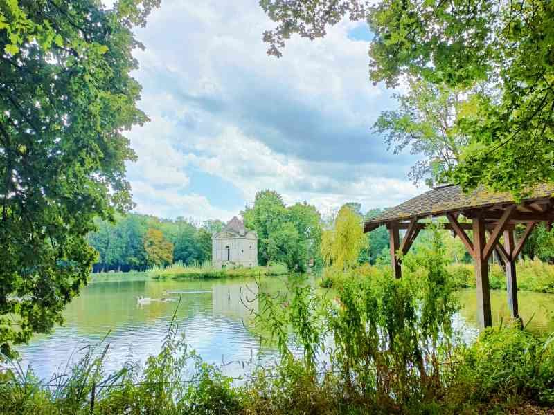 Un lieu avec un lac, un petit bâtiment en pierre au milieu de l'eau et une structure en bois, photo gratuite