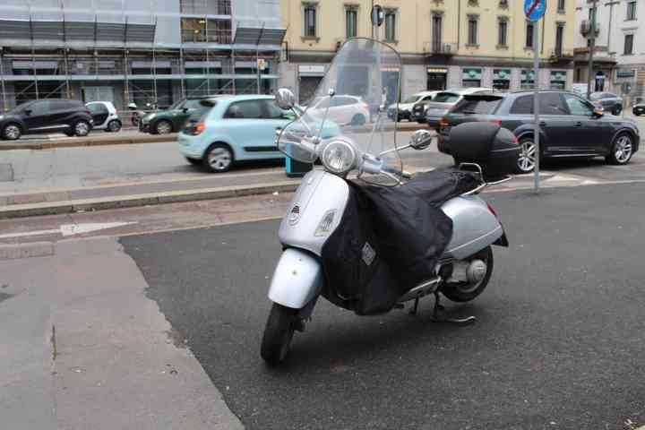 Moto Vespa GTS stationnée au bord d'un goudron dans la ville de Milan Lombardie en Italie photo gratuite