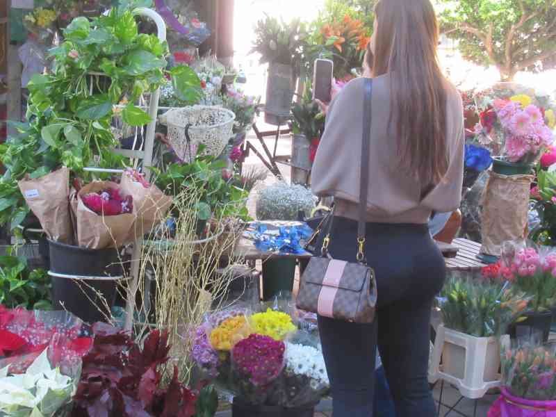 Une femme devant une boutique de fleur, photo gratuite