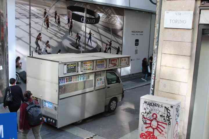 Une petite camionnette aménagée pour la vente, avec des étagères et des présentoirs visibles sur le côté, affichant des produits comme "LEMON SODA" et des logos de boissons gazeuses, photo gratuite