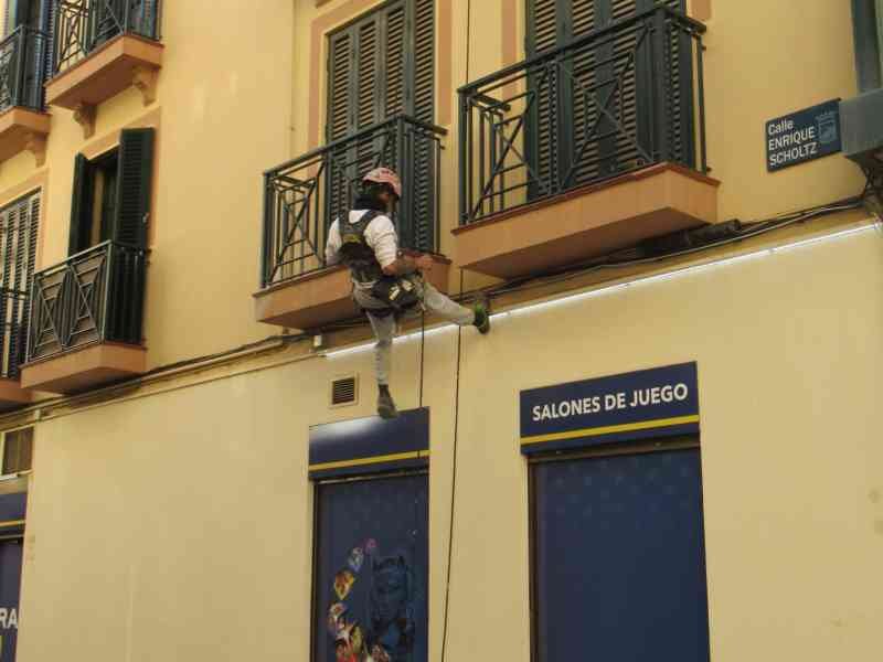 Un ouvrier effectuant des travaux en hauteur sur une façade à Malaga, photo gratuite