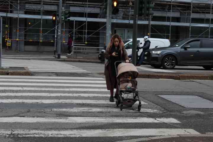 Une jeune maman qui traverse le goudron, passage piétons, avec un bébé sur une poussette dans la ville de Milan Lombardie en Italie photo gratuite