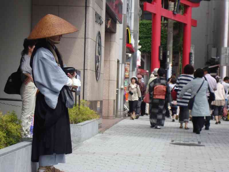 Passersby in traditional Japanese clothing in front of a red Torii gate free photo
