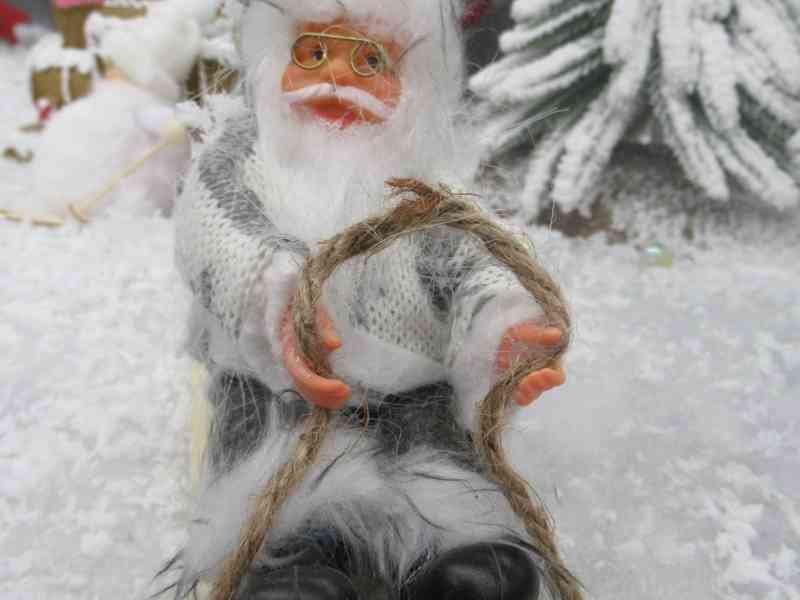 Une figurine décorative de Père Noël assise sur une petite luge en bois, photo gratuite
