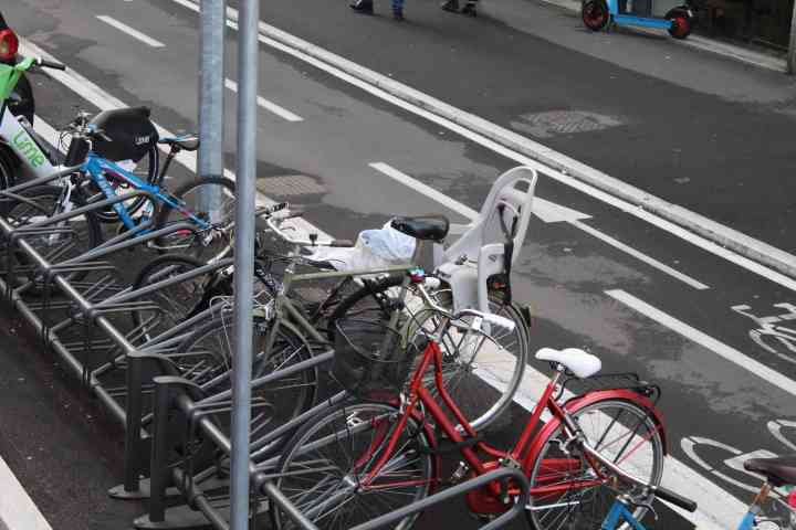 Rental bikes parked in a bike rack next to a bike path, free photo