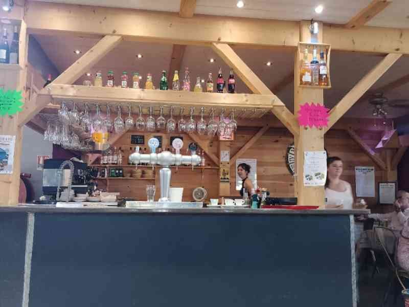 Un long comptoir avec un distributeur de bière et des rangées de verres suspendus au-dessus, photo gratuite