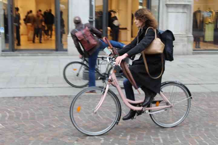 Une femme en déplacement sur un vélo dans la ville de Milan, photo gratuite