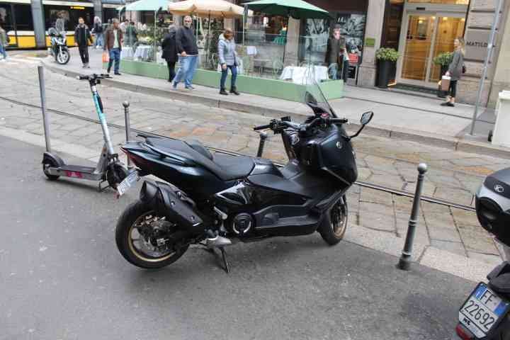 Une moto Yamaha TMAX 560 garée au bord du goudron et une trottinette électrique, photo gratuite