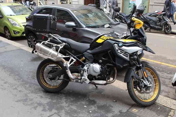 Une moto BMW F 850 GS ou une BMW F 850 GS Adventure garée au bord d'une ruelle de Milan, on y voit d'autres motos et des voitures, photo gratuite