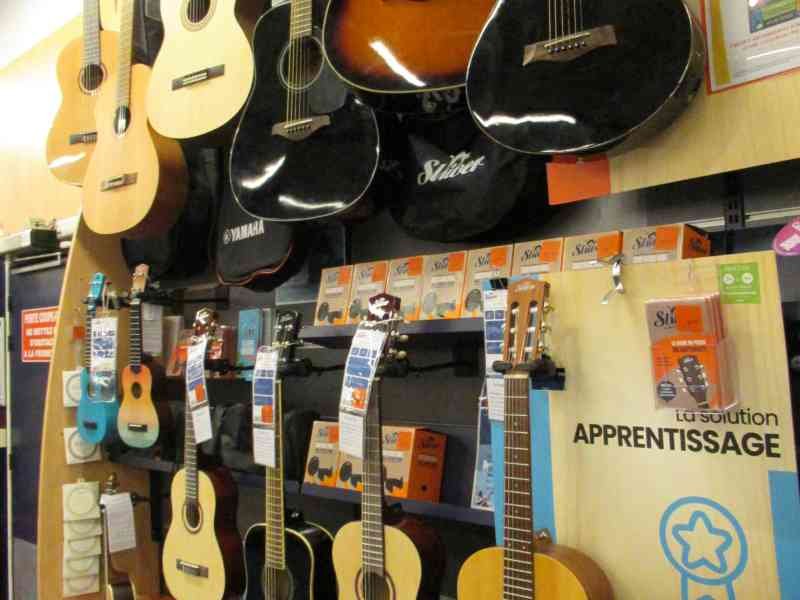 Gamme de Guitares classiques et acoustiques suspendues dans un magasin