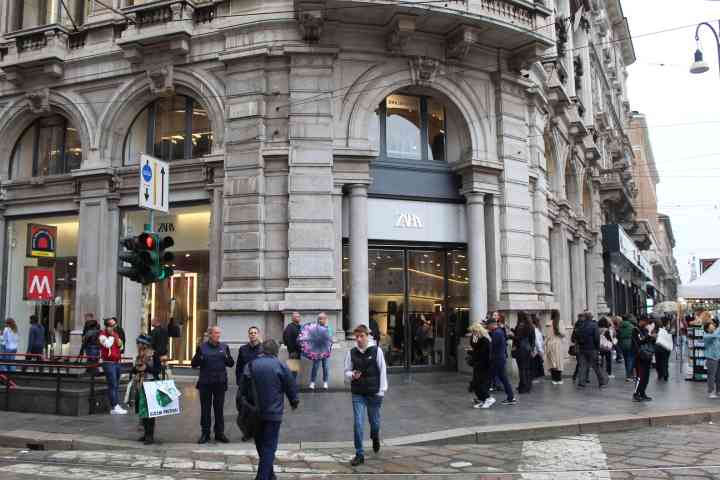 A busy street with a large Zara store on the corner of a building, free photo