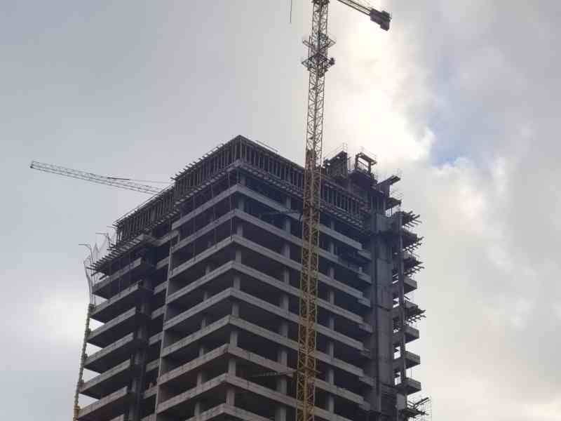 Un grand immeuble en construction avec une grue à tour à côté, photo gratuite