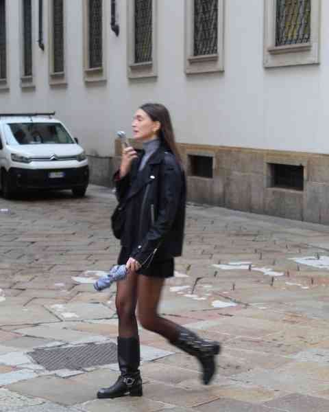 Une femme marchant dans une rue pavée, vêtue d'une tenue décontractée et tendance, photo gratuite