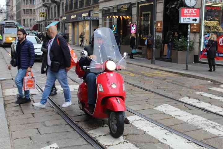 Un scooter rouge garé sur une voie pavée avec des rails de tramway dans la ville de Milan, photo gratuite